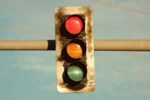 Traffic lights at a U.S. intersection showing red, yellow, and green signals with road signs
